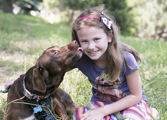 Summer camper getting a kiss from a chocolate lab